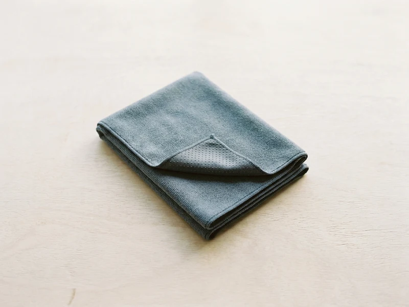A folded grey microfibre yoga mat towel