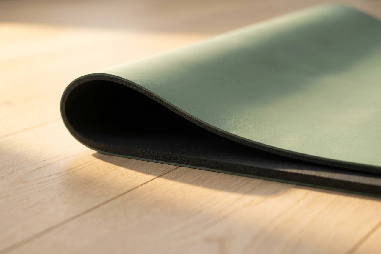 An extremely thin travel mat resting on top of a standard thickness mat, photographed low so the difference is stark