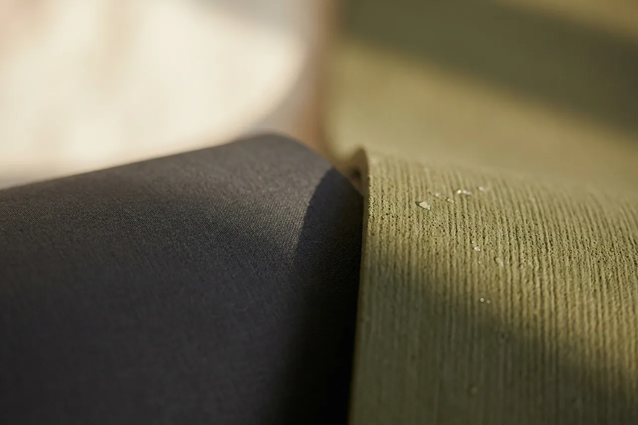Close-up of two yoga mat surfaces side by side, one smooth and dark, one finely ridged and olive green with water droplets on it