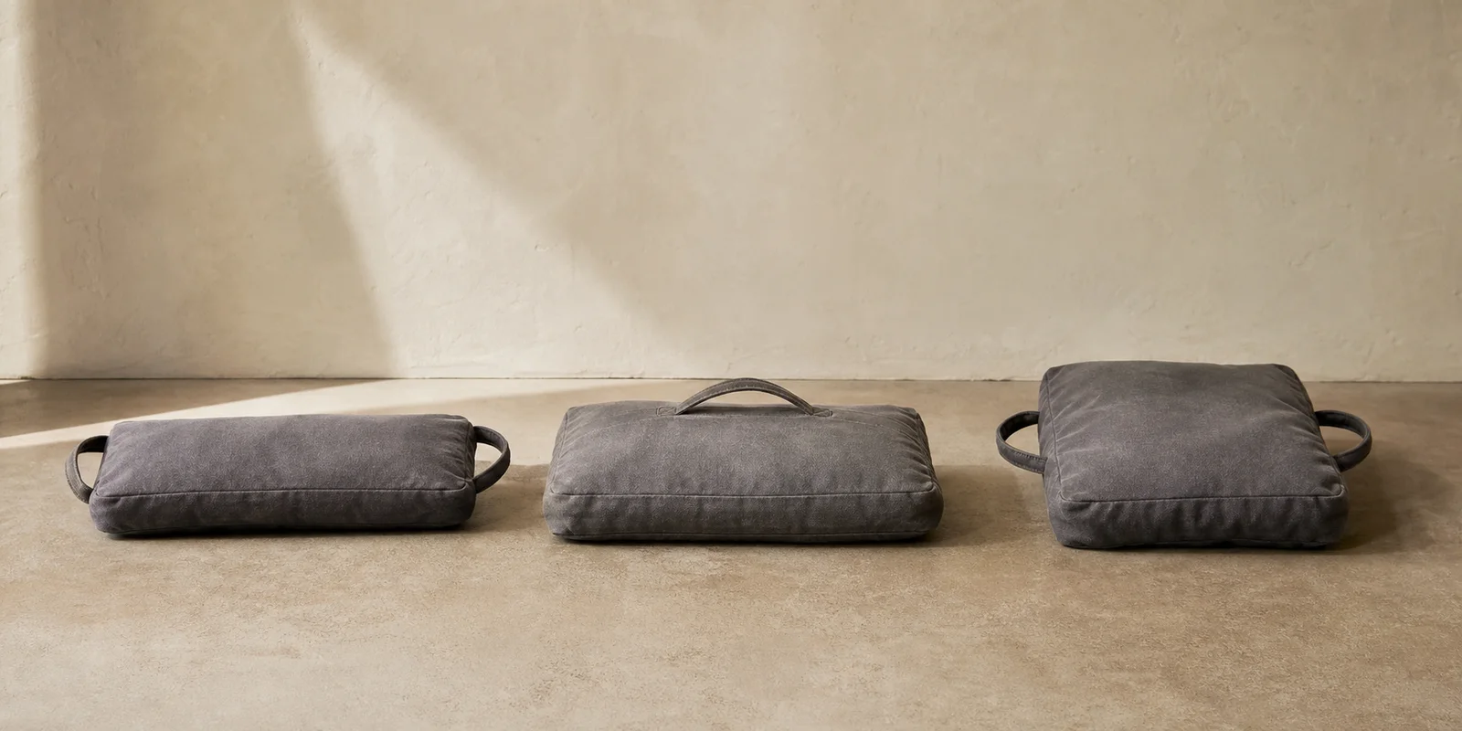 Studio comparison of a slim rectangular yoga sandbag with two handles, wider rectangular bag with one handle and square heavy bag with side handles